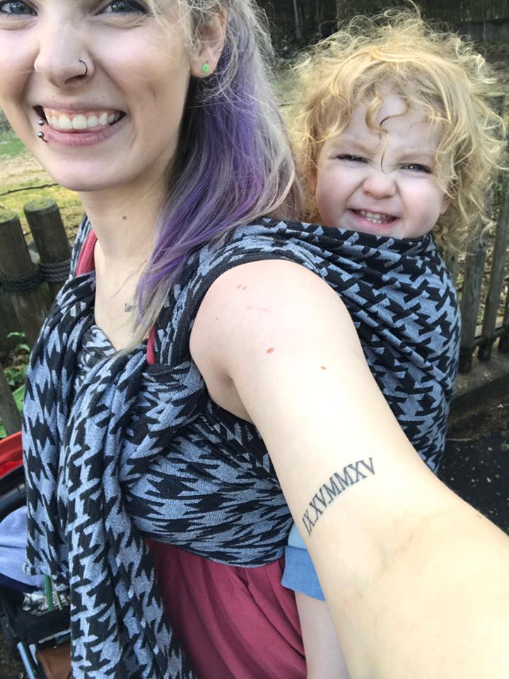 smiling young mother with toddler in back carrier